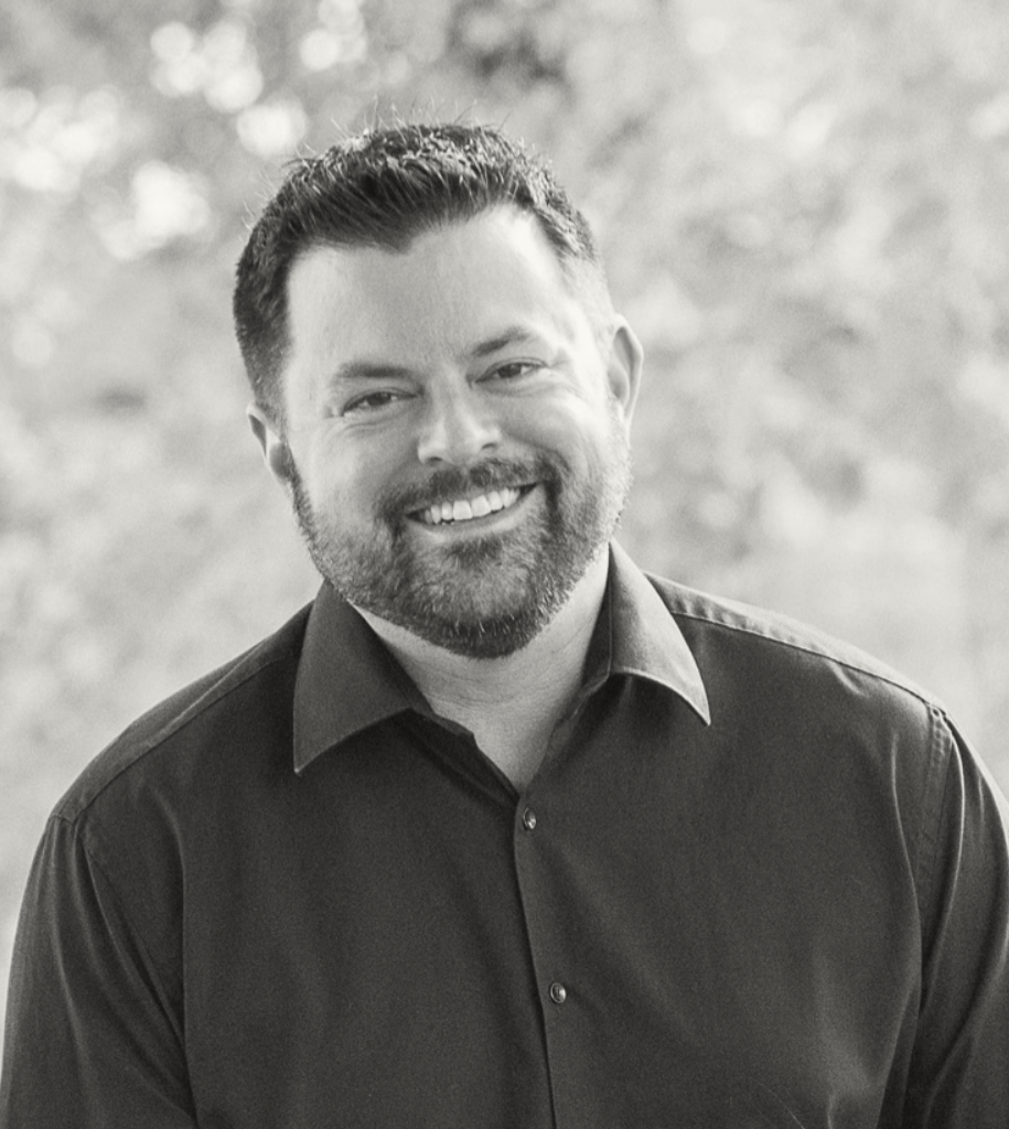 Adam Ferguson, founder of Vantage Credit Union Advisors, smiling outdoors in a black and white portrait.