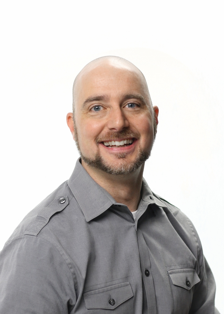 Professional headshot of Brian Oster, smiling in gray button-up shirt against white background